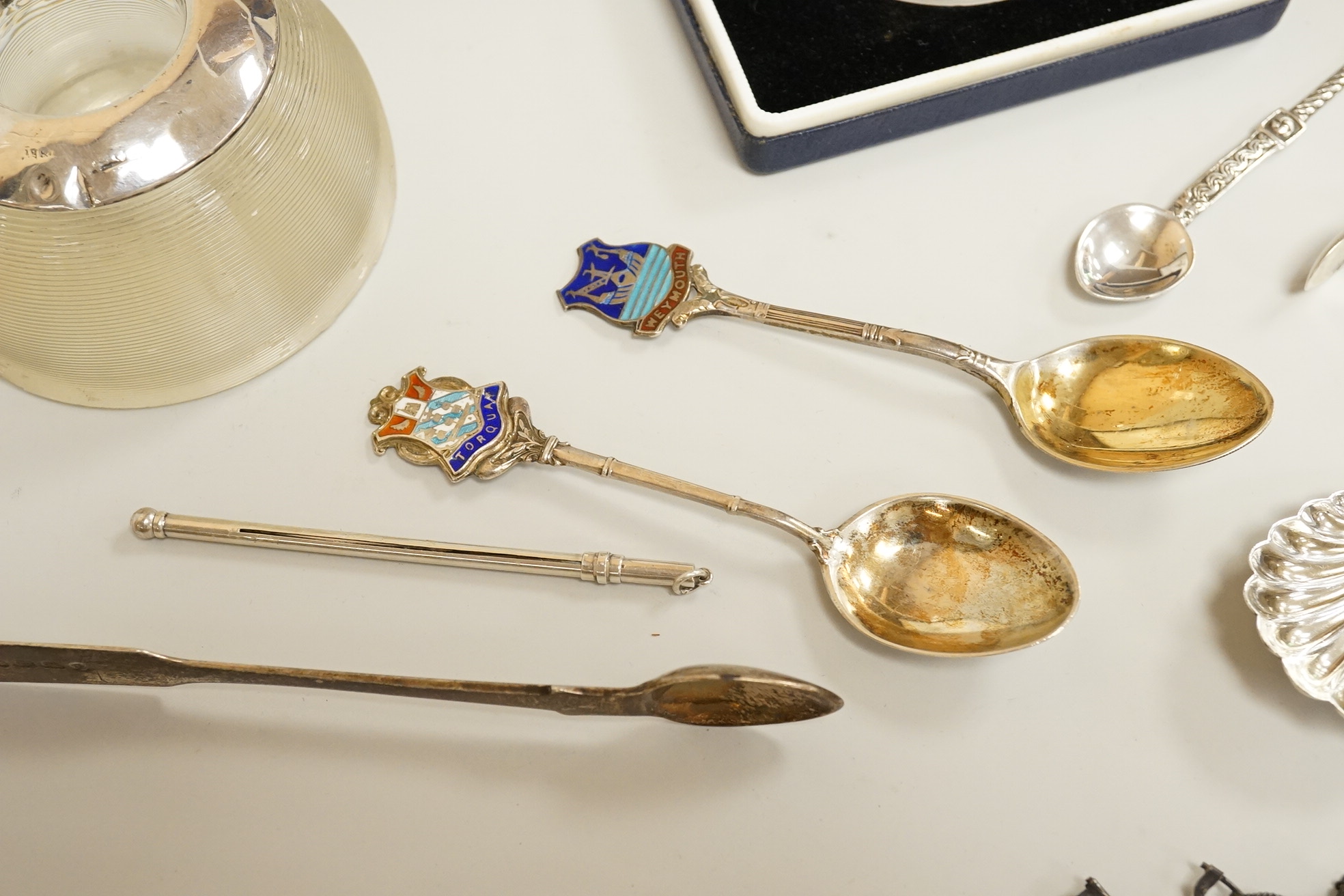 Assorted small silver including a mounted ribbed glass match strike, height 40mm, a small Scottish sterling spoon by Hamish Dawson Bowman, 76mm, a pair of George IV silver sugar tongs, commemorative spoons, an early 20th